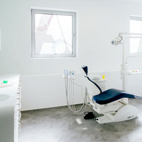 Moderner, heller Zahnarztpraxis-Behandlungsraum mit Dentalstuhl und medizinischer Ausstattung.