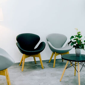 Modern eingerichtetes Wartezimmer mit Designerstühlen, Stehlampe und Pflanze.